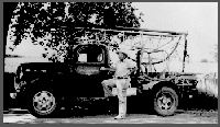 Charlie Keech stands by the new Holemaster Model drilling machine. Tools and operating equipment were purchased in July 1939 for $3,681 and the 1939 3/4-ton Ford cost $750, Summer 1941.